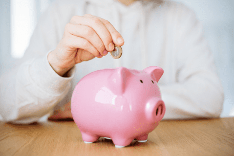 man putting a coin in a piggy bank