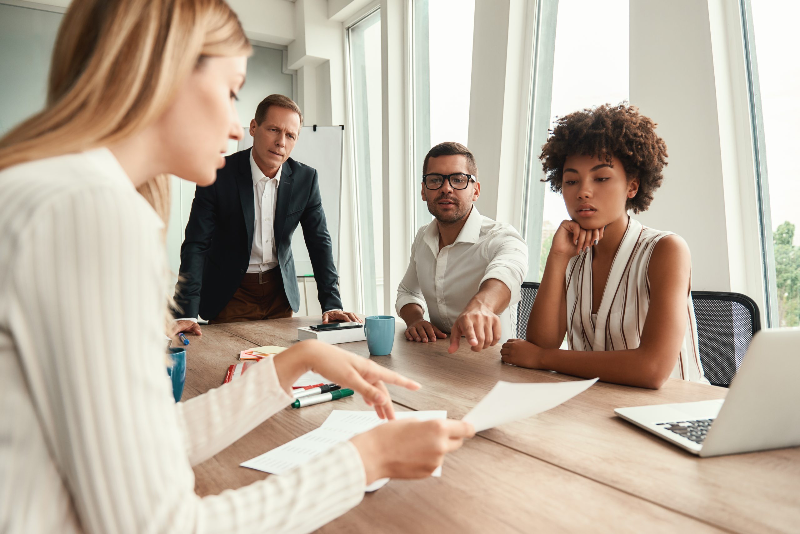 Business Meeting. Group Of Young Business People Looking At Documents And Discussing Something While Sitting At The Office Table