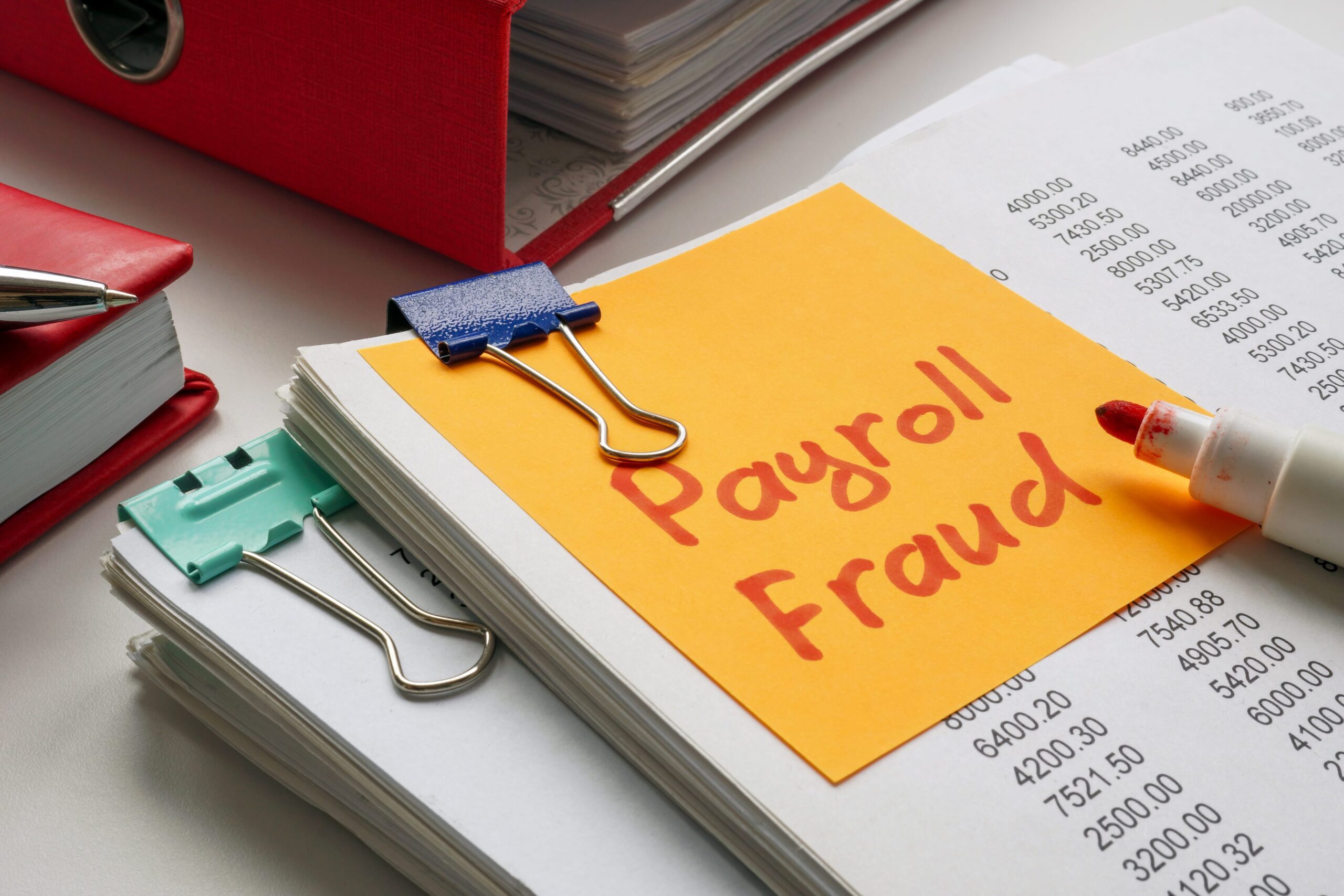 Stack of documents with a note saying payroll fraud
