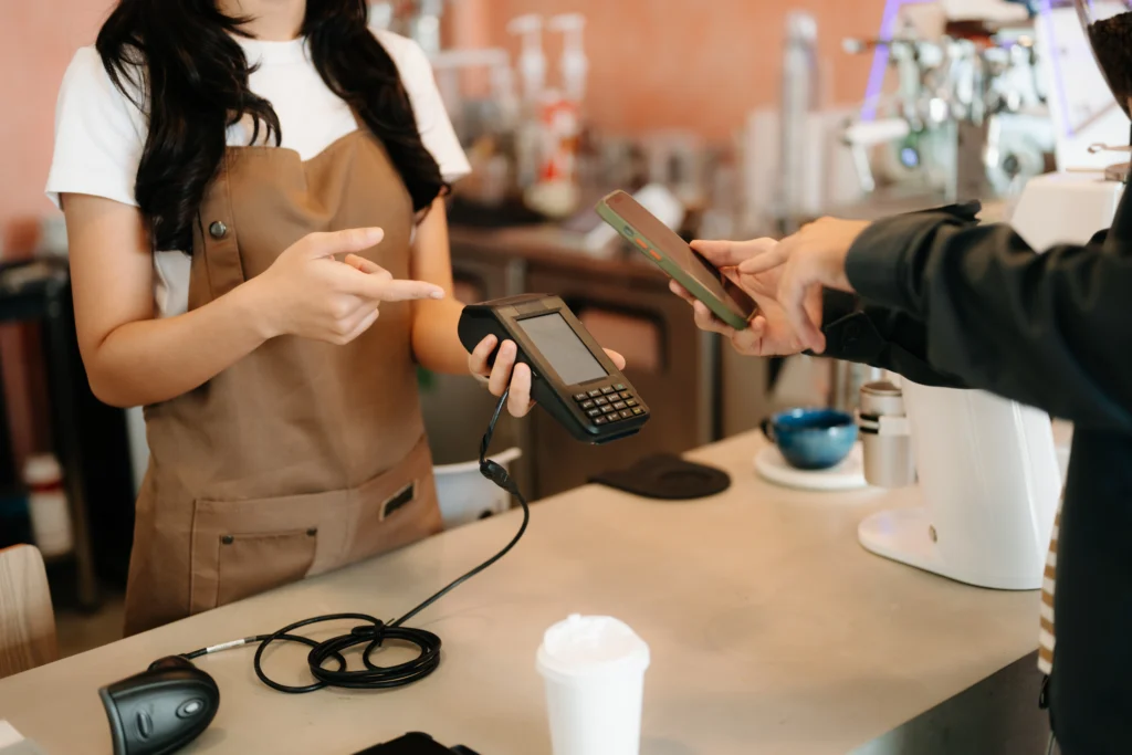 Customer making payment with smartphone at a cafe checkout